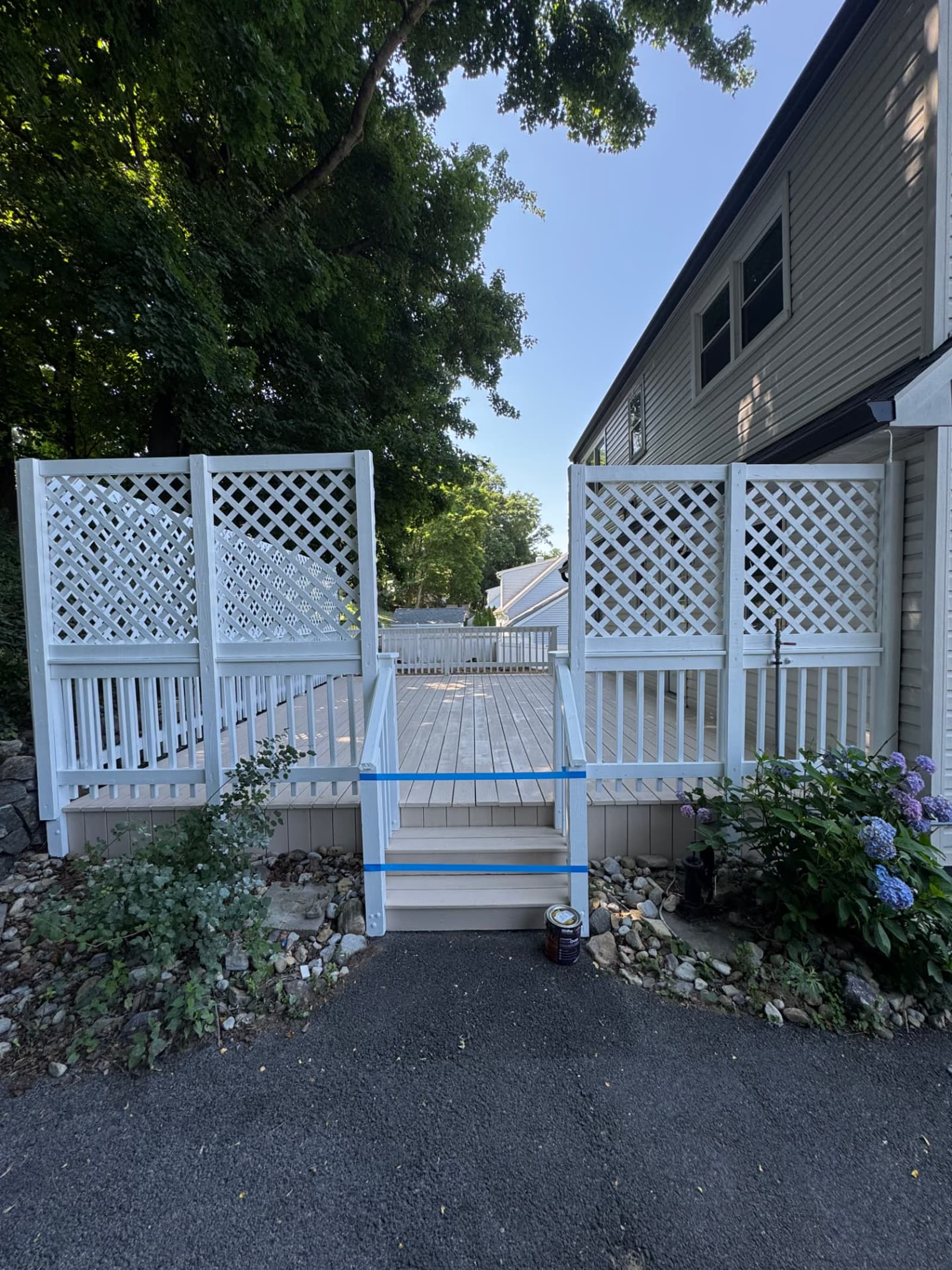 Completed exterior painting project with crisp white deck railings and lattice privacy screens