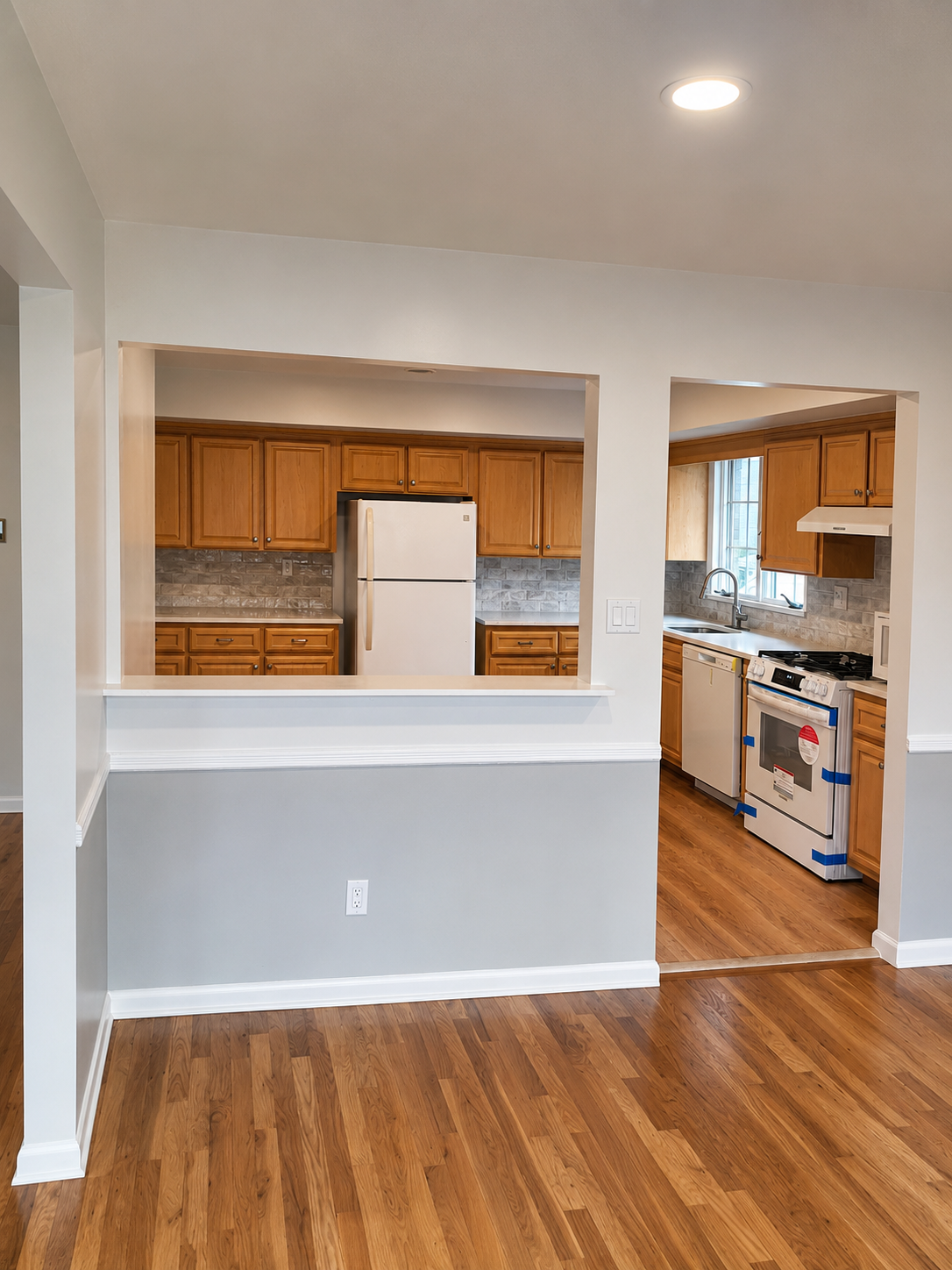 Same living and dining area after interior renovation in Hasbrouck Heights, New Jersey — new hardwood flooring, fresh interior paint, recessed lighting, and refreshed kitchen with new backsplash