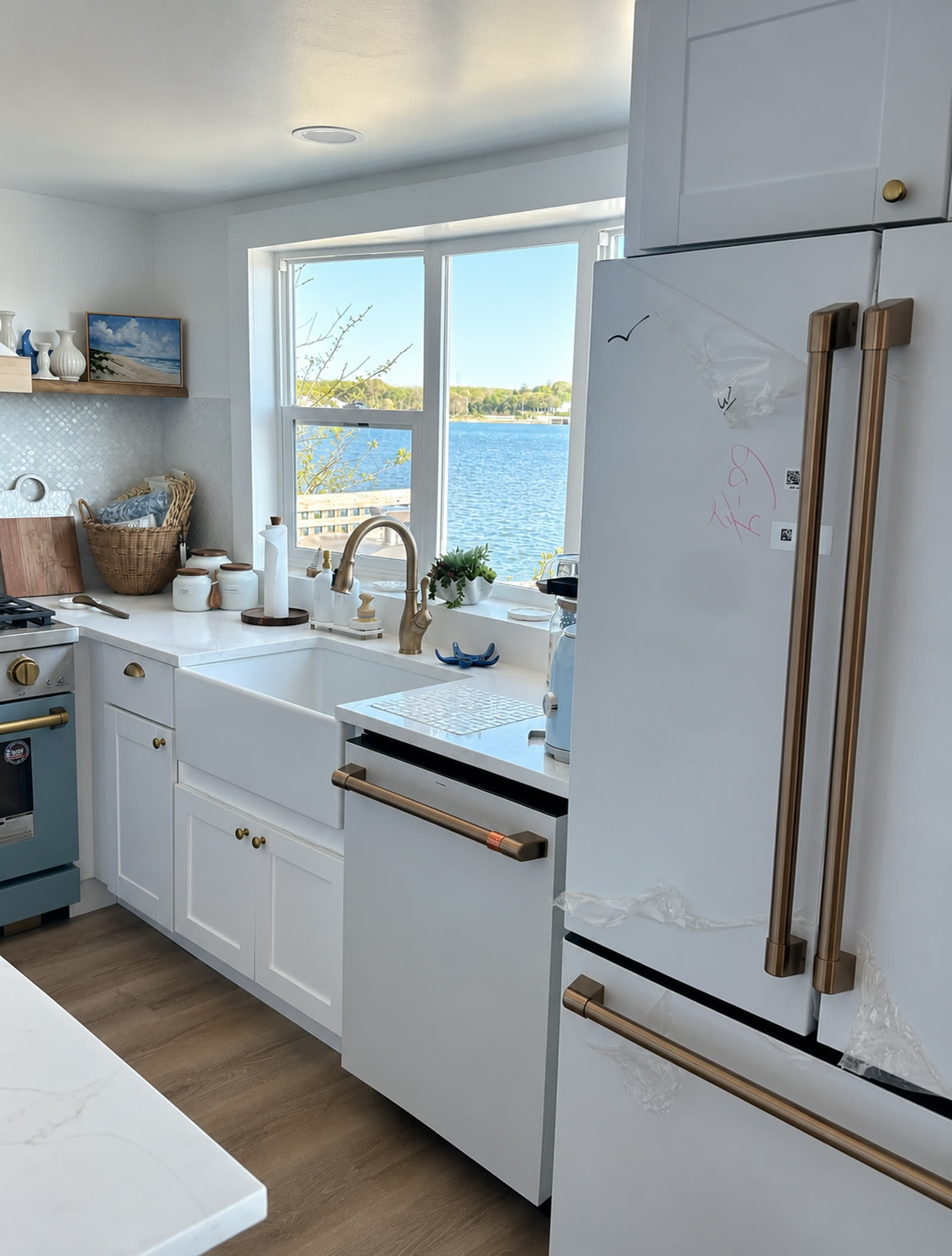 Completed kitchen with farmhouse sink, brass faucet, and waterside window view