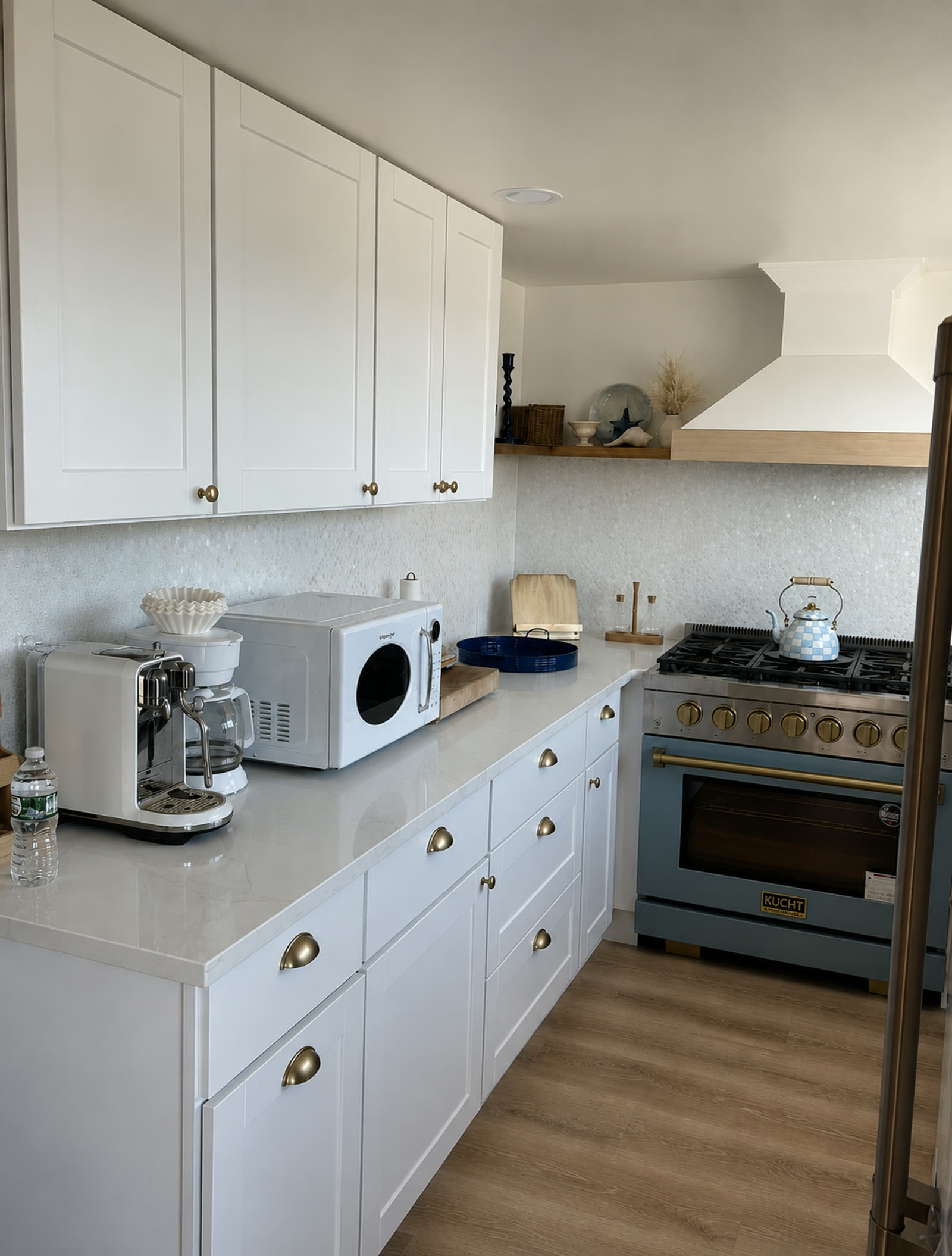 Completed kitchen cabinetry with quartz countertops, tile backsplash, and brass cup pulls