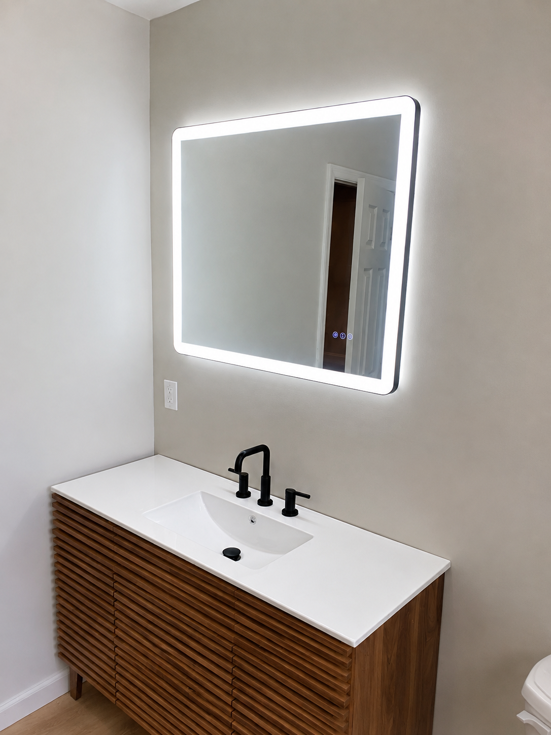 Finished bathroom with slatted walnut vanity, white quartz top, matte black faucet, and backlit LED mirror